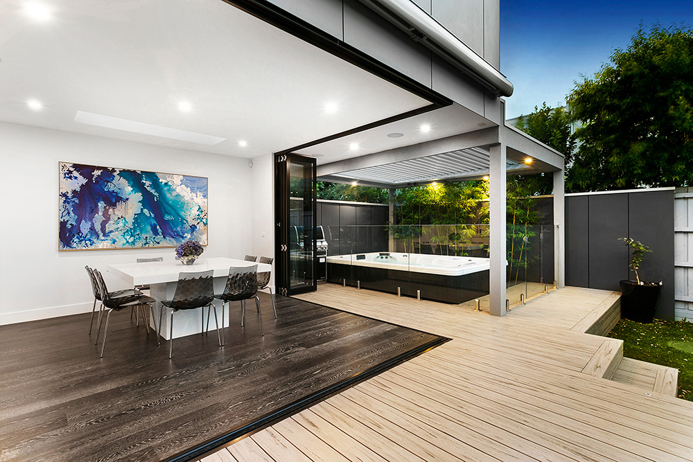 Contemporary dining area with aluminium corner bi-fold doors opening to an outdoor deck and jacuzzi area